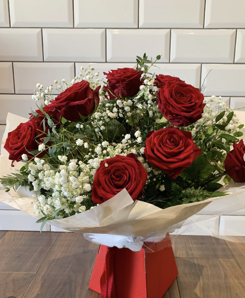 Valentine's bouquet of red roses with gypsophila and eucalyptus, wrapped in cream paper in a red gift box