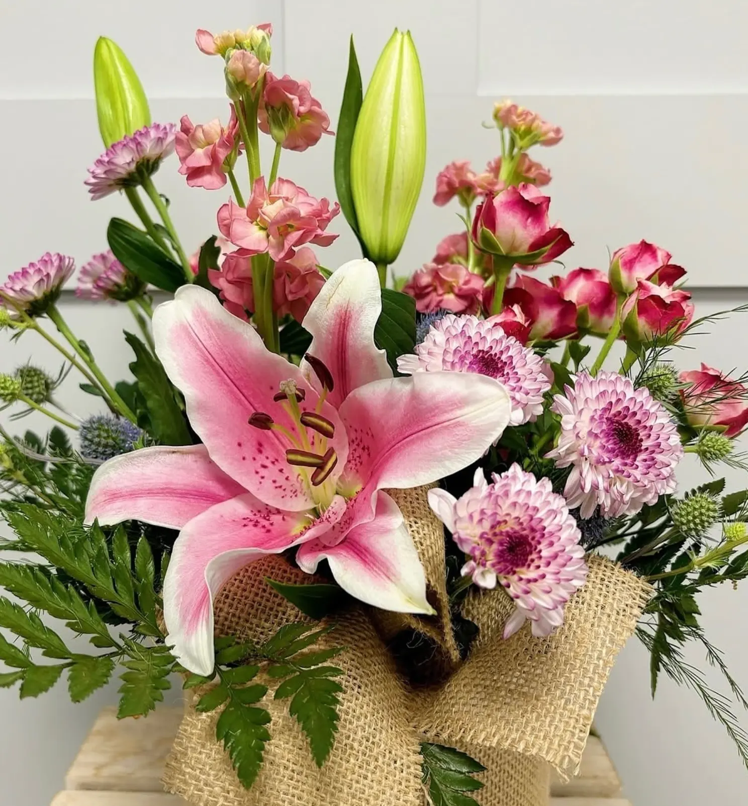 A pink lily and rose arrangement wrapped in hessian