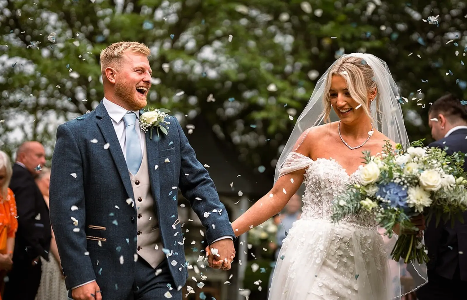 A bride and groom celebrating outside the cafe with confetti