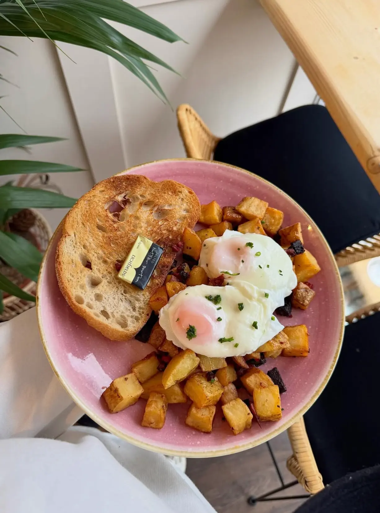 Poached eggs and diced potatoes with chorizo on a pink plate at Leaf + Bean